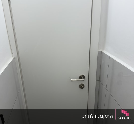 דלת לבנה עם ידית מתכת בחדר אמבטיה
